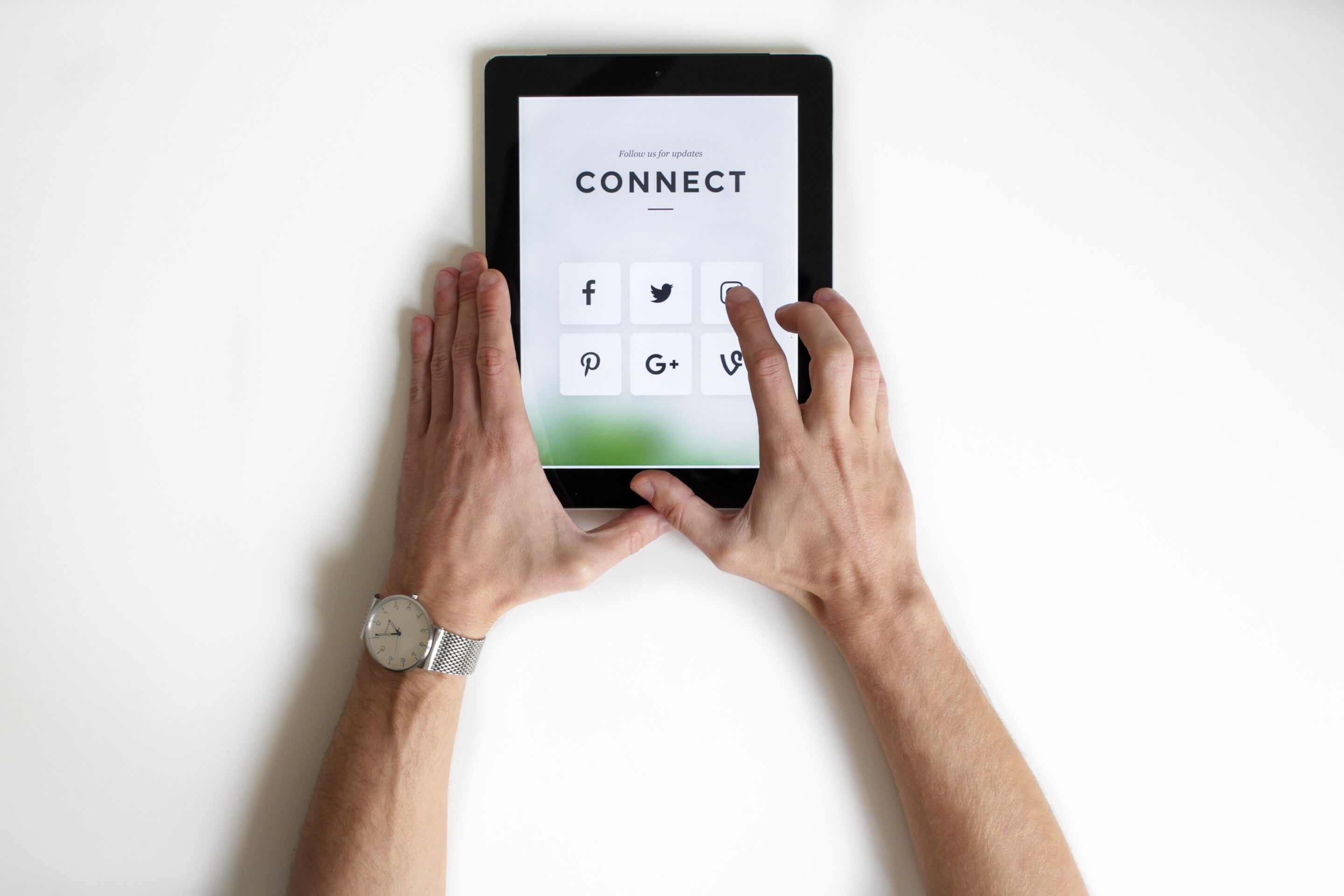 Hands using a tablet that says "connect" with various social media icons